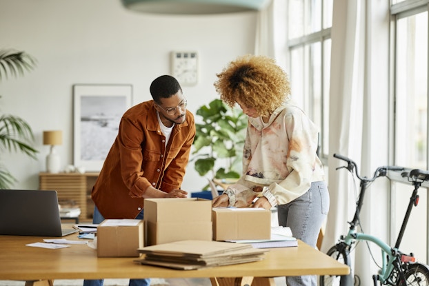  Two people working inside a home office packing boxes.