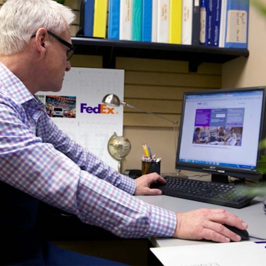 A man looks at a FedEx report on his desktop computer.