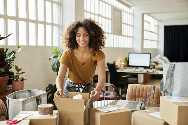 Small business owner packing products in shipping boxes.