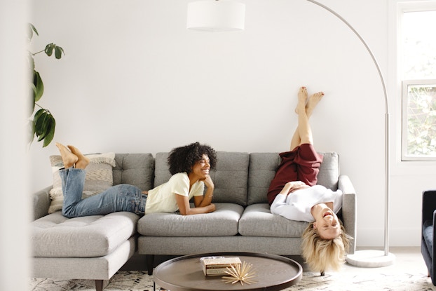 two women relaxing on a fernish couch