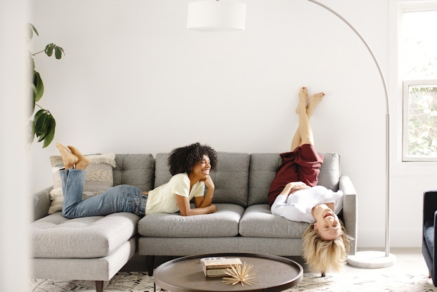  two women relaxing on a fernish couch