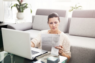  woman looking at paperwork and laptop 