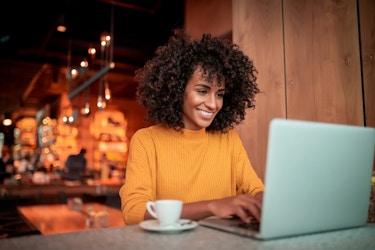 Happy woman working on laptop in a coffee shop.