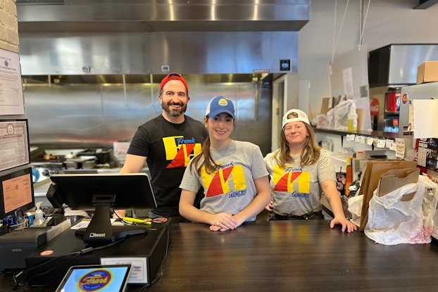 Employees of Frank Gourmet Hot Dogs inside their restaurant.