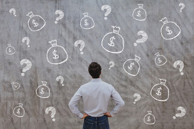 man standing in front of wall with dollar signs drawn on it