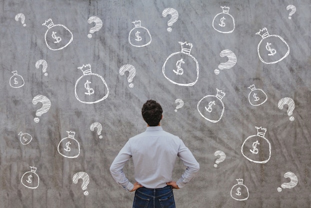  man standing in front of wall with dollar signs drawn on it