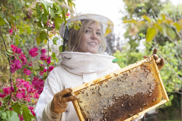  Hilary Kearney, founder of Girl Next Door Honey, wearing a beekeeping outfit and tending to bees.