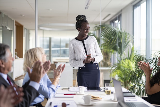Smiling professional woman presenting to colleagues in a conference room.
