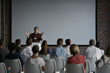  Person giving a speech to a group of people. 