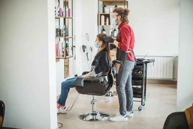 woman getting hair done in salon with masks on