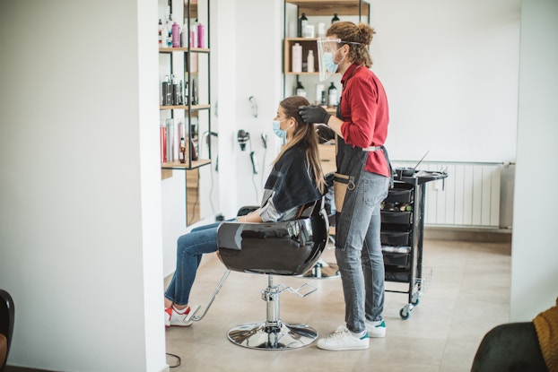  woman getting hair done in salon with masks on