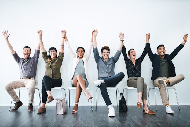 team of employees holding hands in the air