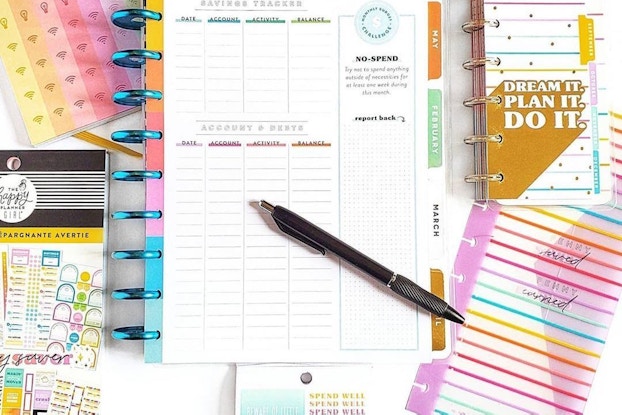 Product shots of Happy Planner notebooks on a table with a pen.