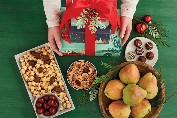 Display of Harry & David food items with a stack of wrapped presents on a green tablecloth.