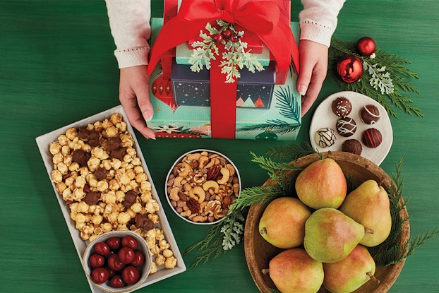  Display of Harry & David food items with a stack of wrapped presents on a green tablecloth.