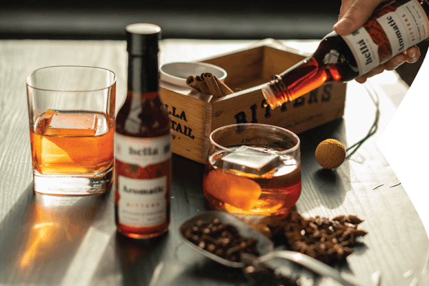Person mixing a cocktail with Hella Cocktail Co. bitters.