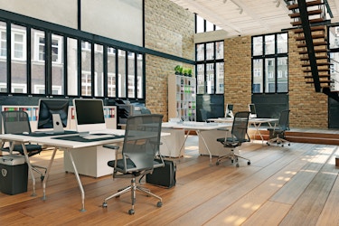  Modern office setting with desks and large windows. 