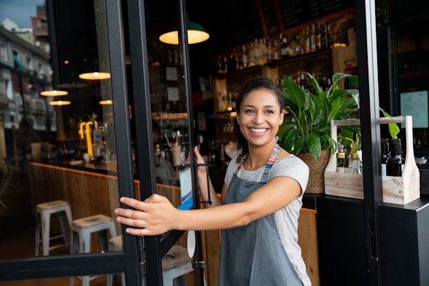 hispanic business owner opening door