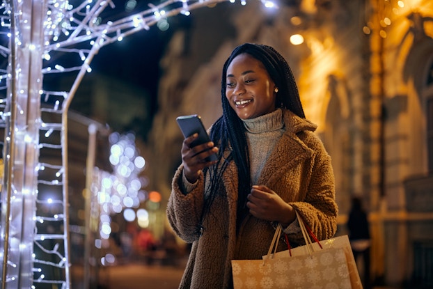  Woman shopping on her phone outside during the holidays.