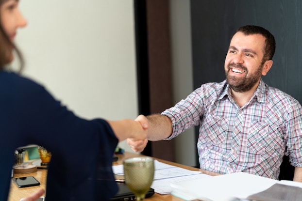 man shaking hands with woman at interview