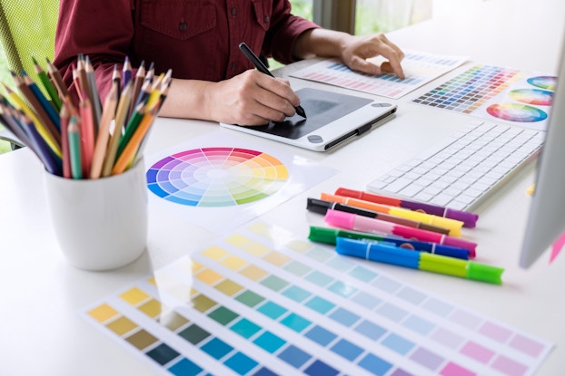  Image of female creative graphic designer working on color selection and drawing on graphics tablet at workplace.