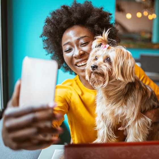Happy smiling woman taking a selfie with her puppy.