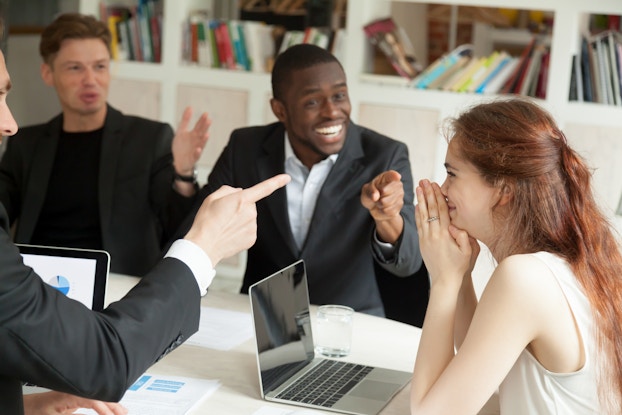 Employees happily celebrate colleague's achievement who appears shy.
