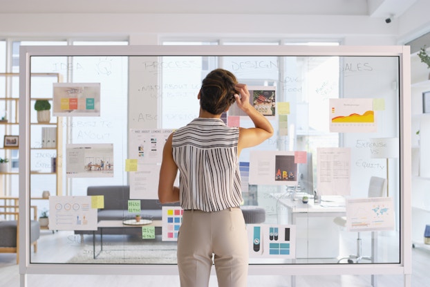 woman writing on clear board in office