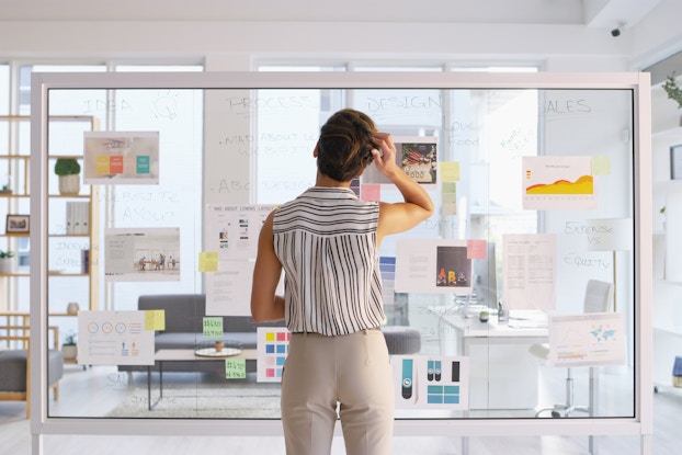  woman writing on clear board in office