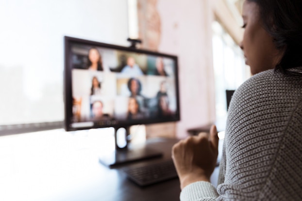 Woman working remotely tuned into a video conference with colleagues.