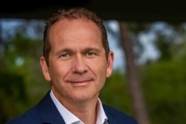  A headshot of Mike Davis, CEO of Mathnasium. Mike Davis is a middle-aged white man with dark hair. He is wearing a dark blue blazer over a white button-up shirt. 