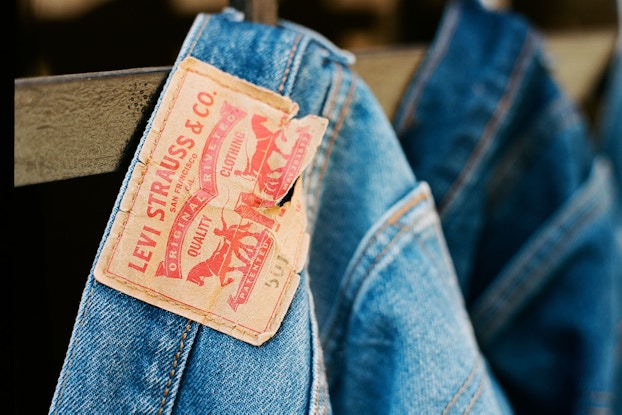 Pairs of Levi's jeans hanging from belt loop in a row.