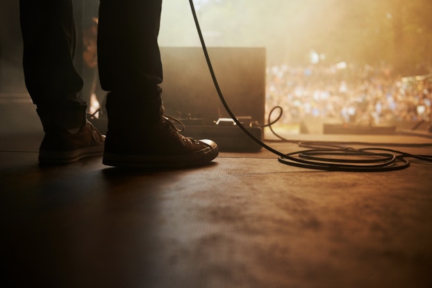  person's feet on stage at a live music venue