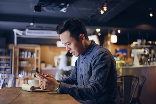 Man working in cafe at a table going over receipts.