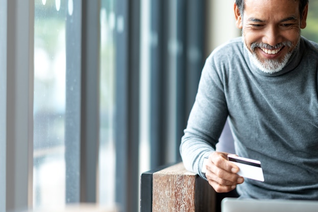  A man holding a credit card shops on his laptop.