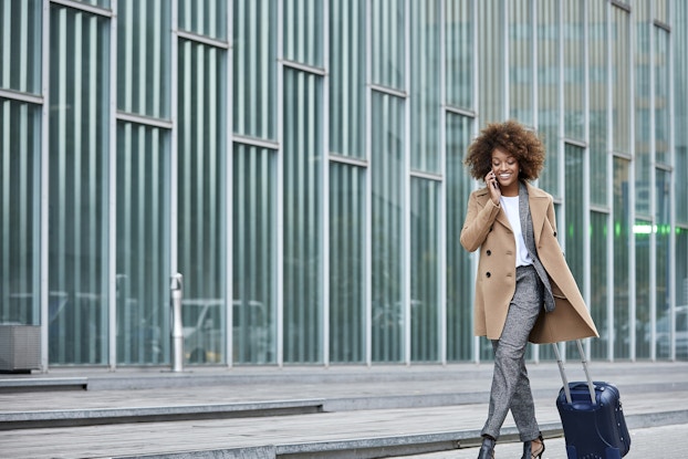 businesswoman on phone walking with suitcase