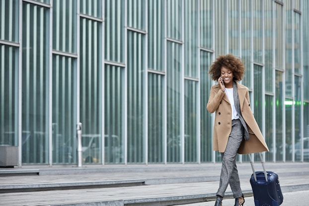  businesswoman on phone walking with suitcase