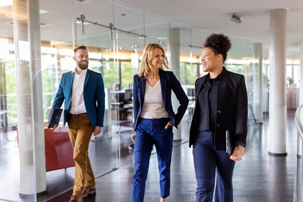 Team of employees walking through the bright open hallway of an office.