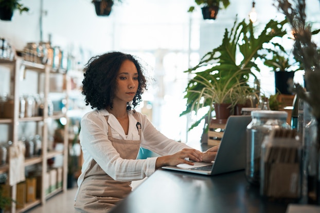  Woman business owner inside her business working on laptop.