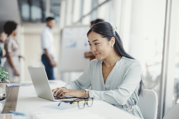 Woman working on laptop in a bright office.