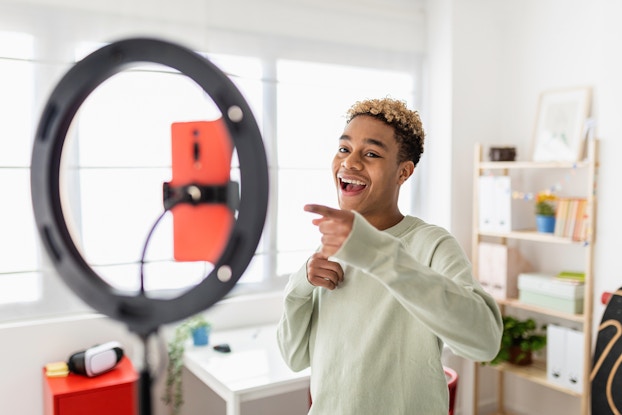  Content creator recording himself in front of a phone and ring light.