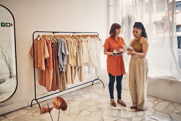 Customer in a clothing boutique speaking with an employee.