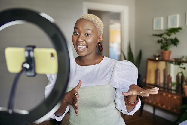  Influencer recording herself via phone in front of a ring light.