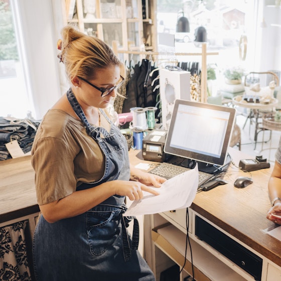 Two colleagues going over receipts a the front desk of their retail business.