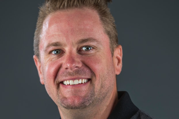 A headshot of Michael Browning, the CEO of Unleashed Brands, against a dark gray background. Michael is a white man with dark blond hair and green eyes, and he is smiling.