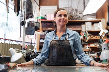  A young woman is standing in a leather and shoe repair shop. 