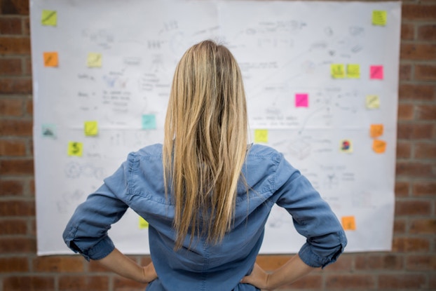 woman looking at whiteboard with notes