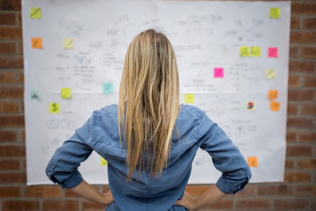  woman looking at whiteboard with notes