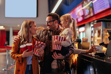  Family smiling at a movie theater heading into the theater after buying concessions. 