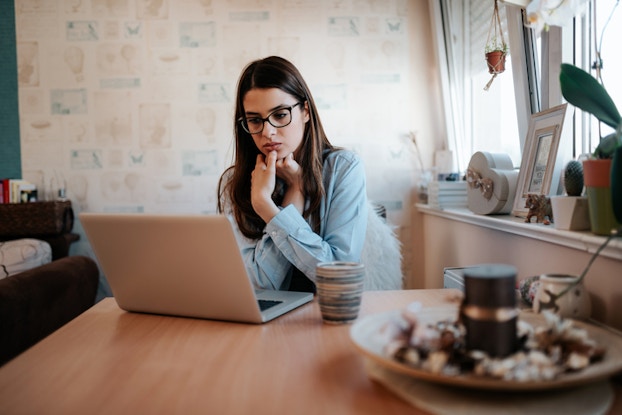 woman thinking while looking at laptop